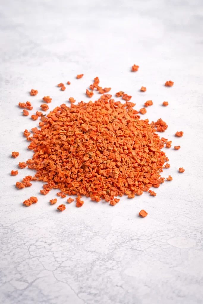 Carotte déshydratée en morceaux sur fond blanc – ingrédient naturel pour industrie alimentaire et B2B